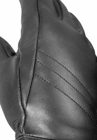 Schwarzer Lederhandschuh mit strukturiertem Obermaterial, gesteppten Details und geschwungenen Fingern, der feine Handwerkskunst und Langlebigkeit hervorhebt.