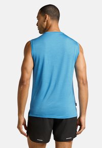 Canotta sportiva da uomo in un blu vivace, caratterizzata da una texture liscia, scollo rotondo e spacchi laterali per la mobilità, abbinata a pantaloni shorts neri.