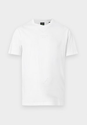 Camiseta blanca lisa de manga corta con cuello redondo, con un sutil logo en relieve en el pecho y una etiqueta de marca negra en el interior del cuello.