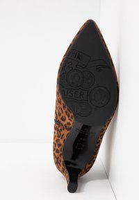 Chaussure à talon haut à bout pointu imprimé léopard vue de la semelle côté avec logo embossé et taille 41,5 visible sur la semelle noire.
