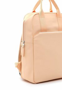 Persikanvärinen reppu, jossa on sileä kumipinta, kahdet yläkahvat ja etutasku vetoketjulla. Sivulla on verkkokangaspaneelit.