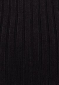 Svart ribbat tyg med vertikala ränder, texturen är mjuk och elastisk, med en lätt lyster. Designen är kroppsnära och sömlös.