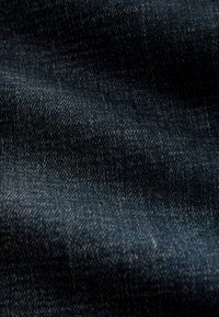 Ciemnoniebieska tkanina dżinsowa o gładkiej fakturze, charakteryzująca się delikatnym połyskiem oraz subtelnymi różnicami w kolorze i wzorach splotu.