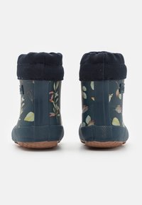 Granatowe gumowe kalosze z kwiatowym wzorem, teksturowanym granatowym mankietem i brązową gumową podeszwą. Posiadają gładkie wykończenie i zaokrąglony kształt palców.