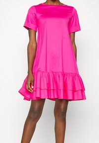Rosa Kurzarmkleid mit Rundhalsausschnitt und geschichtetem Volant-Saum. Glatte Textur und knielang, hergestellt aus leichtem Material.