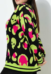 Schwarzer Pullover mit neongrünen und pinken Totenköpfen sowie abstrahierten Mustern. Gerippte Bündchen und Saum mit kontrastierenden Streifen. Stricktextur, lockere Passform.