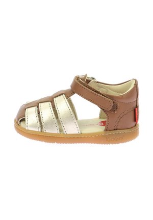 Sandalo in pelle marrone con dettagli metallici dorati, design aperto sulla punta, cinturino regolabile, suola in gomma e logo "Kickers" sul lato.