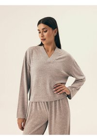 Jasnoszary, długorękawowy top w serek wykonany z miękkiego, teksturowanego materiału, połączony z dopasowanymi spodniami. Swobodny, luźny krój z krótkim fasonem.