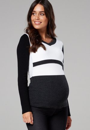 Black and white maternity sweater, featuring a V-neck, ribbed texture, and color-block design with a fitted silhouette and long sleeves.