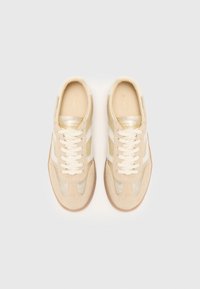 Beige semsket sneakers med hvite lærstriper, snøring, lysfargede såler og en glatt teksturert overdel. Gullmerker er til stede.