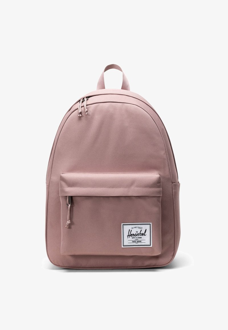 Rosa tygryggsäck med en böjd form, framfick för blixtlås och en vit varumärkesetikett. Har dubbla övre blixtlås och justerbara axelremmar.