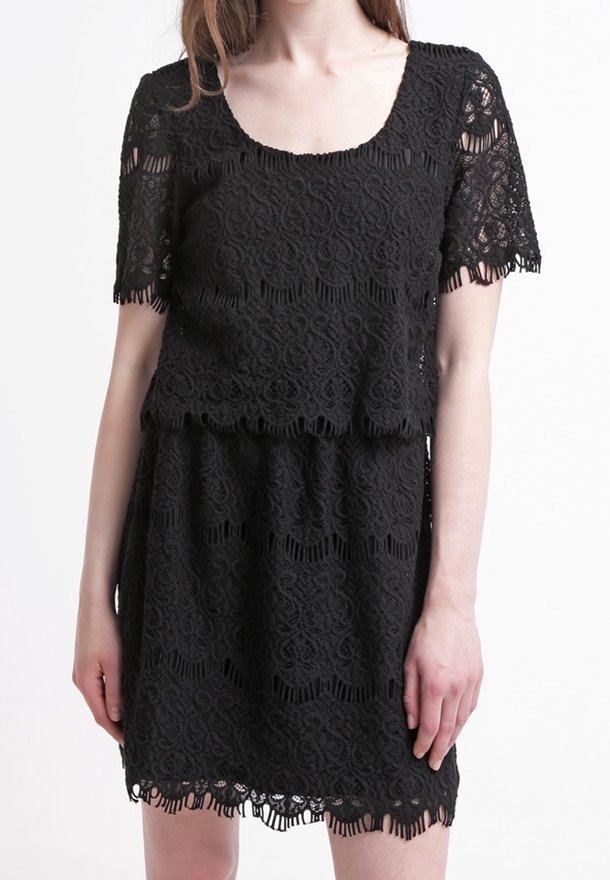Svart spetsklänning med ett lagerdesign, med korta ärmar, fyrkantig uringning och scalloperade kanter. Invecklade blommönster synliga.