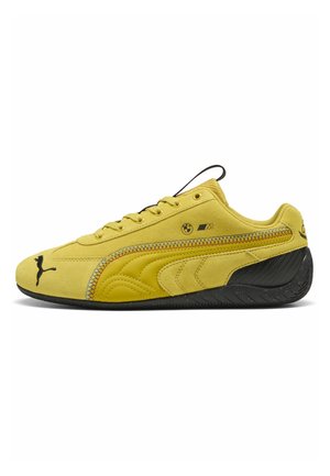 Sneaker Puma in camoscio giallo con suola nera, logo BMW M e logo Puma nero su punta, lato e tallone, vista dal lato esterno.