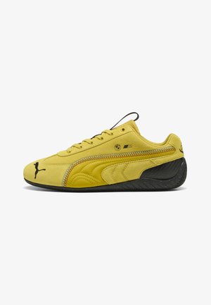 Sneaker Puma in camoscio giallo con suola nera, logo BMW M e logo Puma nero su punta, lato e tallone, vista dal lato esterno.