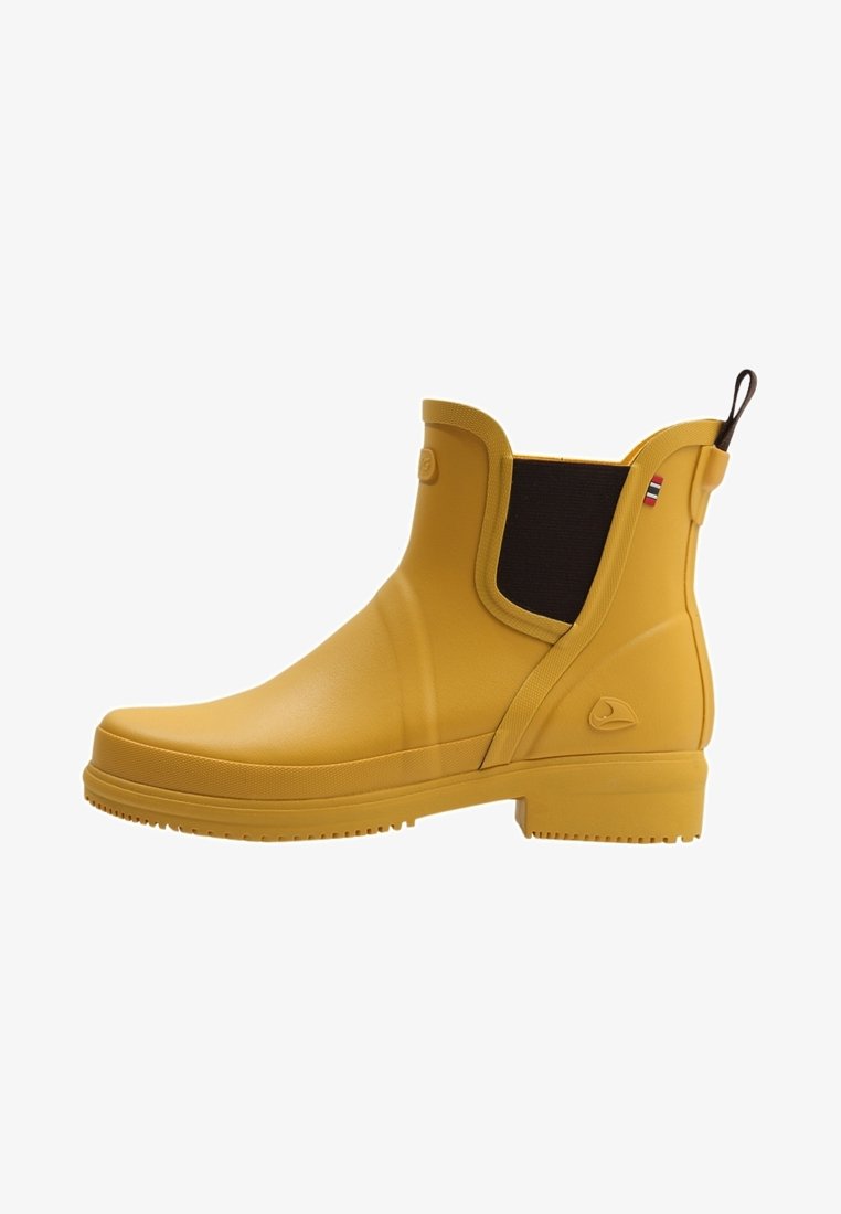 Botas de tobillo de goma amarillas con una textura suave, paneles laterales elásticos y una lengüeta. Presentan un pequeño logo y un acento a rayas.