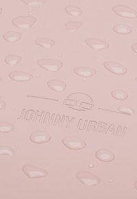 Superficie texture rosa con rigonfiamenti in rilievo e logo in rilievo "JOHNNY URBAN". Presenta una finitura liscia e lucida e dettagli di design sottili.