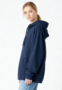 Sweat à capuche oversize bleu marine avec une poche avant, une capuche à cordon et des poignets côtelés. Confectionné dans un tissu doux et confortable avec une texture lisse.