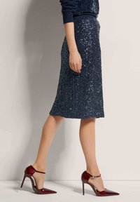 Donker sequined midi-jurk met een aansluitend ontwerp, gecombineerd met bordeauxrood gepatenteerd leren hoge hakken met een enkelbandje.