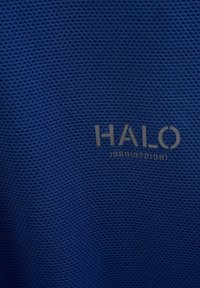 Blå texturerad tyg med ett mesh-mönster och en framträdande "HALO"-logotyp. Har numeriska detaljer: "196819721981" i en kontrasterande färg.