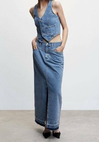 Denim two-piece featuring a cropped vest with buttons and a long skirt with a front slit, both in a light blue wash and relaxed fit.