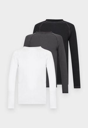 Tre långärmade t-shirts staplade ovanpå varandra: en vit, en grå och en svart. Tillverkade av mjukt tyg med rundade halsringningar och raglanärmar.