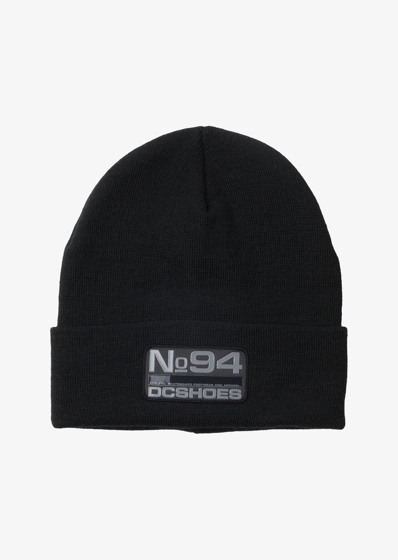 Black knit beanie with a folded cuff, featuring a rectangular gray patch with "No94 DC Shoes" embossed in white. Soft, stretchy material.