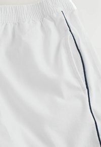 Shorts blancs à taille élastique avec poches latérales et une fine bande verticale bleu foncé le long de la couture extérieure.