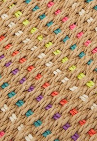 Kudottu matto, joka on valmistettu vaaleanruskeista luonnonkuiduista, ja jossa on elävävärisiä haroja vaaleanpunaisena, vihreänä, purppurana ja sinisenä, sekä teksturoitu pinta.