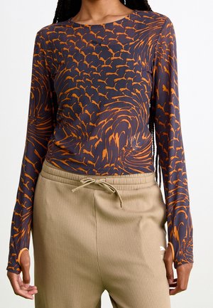 Donkerblauwe langlopende shirt met oranje draaiende patronen, gemaakt van een zachte stof, gecombineerd met beige geribbelde sweatpants met een trekkoord.