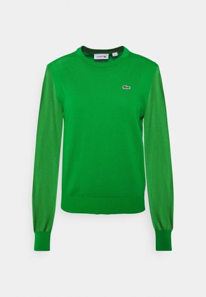 Zielony sweter z pulowerem z długimi rękawami. Posiada okrągły dekolt i prążkowane mankiety. Na piersi znajduje się logo Lacoste w kontrastującym kolorze.