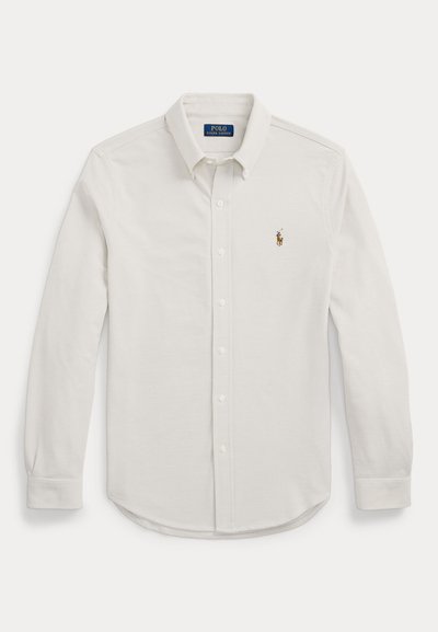 White long-sleeve button-up shirt made from cotton fabric. Features a pointed collar and an embroidered logo on the left chest.