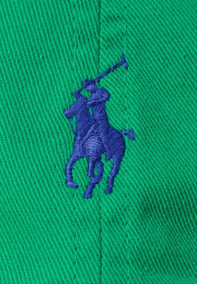 Tecido verde com um padrão texturizado exibindo um proeminente logo de jogador de polo bordado em azul, destacando o contraste e os detalhes na costura.