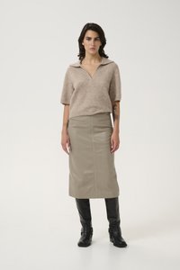 Beige ullblanding kortermet polo-top med V-hals. Olivengrønn skinn midi-skjørt, knelengde svarte skinnstøvler med spenne detaljer.