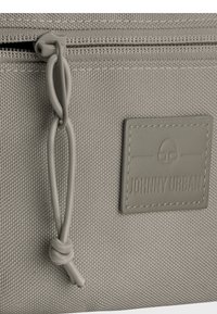 Borsa in tessuto grigio con superficie strutturata, dotata di chiusura a zip e di un'etichetta simile alla pelle con la scritta "JOHNNY URBAN" in rilievo.