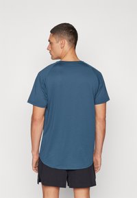 T-shirt sportivo blu scuro con maniche corte, colletto rotondo e tessuto texturizzato. Orlo leggermente arrotondato sul retro, design semplice.