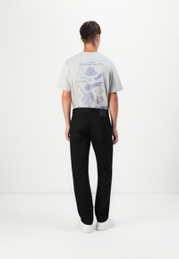 Light gray shirt with blue food-themed graphics on the back, paired with black pants and white sneakers. Simple, casual design.