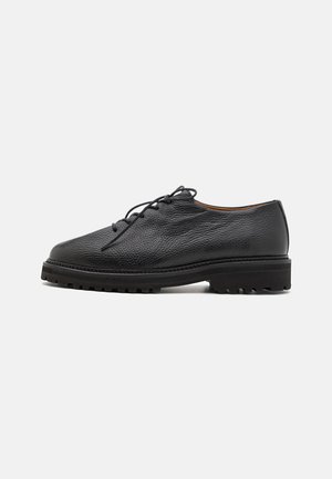 Black leather shoes featuring a textured finish, round toe, lace-up design, and rugged sole with pronounced tread pattern.