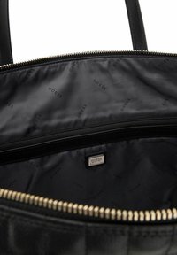 Sac à main noir avec fermeture éclair, présentant un extérieur lisse, des accents en doré et une doublure intérieure à motif logo.