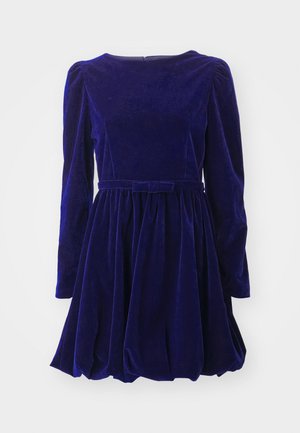 Rochie din catifea de culoare albastru închis, cu mâneci lungi, decolteu rotund și talie strânsă. Dispune de o fustă plisată și un rită asortat.