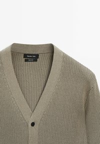 Hellgrauer Cardigan aus 100 % Baumwolle. Verfügt über einen V-Ausschnitt, ein strukturiertes Strickmuster und einen Knopfverschluss an der Vorderseite.