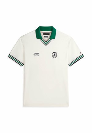 Polo blanco de manga corta con cuello verde, puños a rayas y logotipos: "Tommy Hilfiger EST. 1985" y un escudo en el pecho.