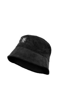 Black bucket hat made of corduroy fabric. Features a stitched logo patch and a wide, flexible brim. Textured surface with ribbed detail.
