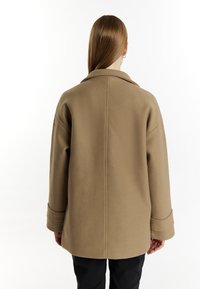 Bruine wolmixjas met een brede kraag, verlaagde schouders en lange mouwen. Heeft een strakke silhoutte en een gestructureerde afwerking.