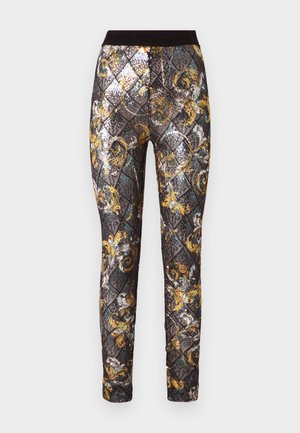 Melnas un zelta rakstainas leggi, kurām ir dimanta dizains ar pērlītēm, elastīga jostu un sarežģīti ziedu akcenti.