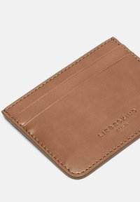 Brązowy skórzany etui na karty z czterema przegródkami, gładką fakturą, tłoczonym logo oraz kontrastującym przeszyciem na krawędziach.