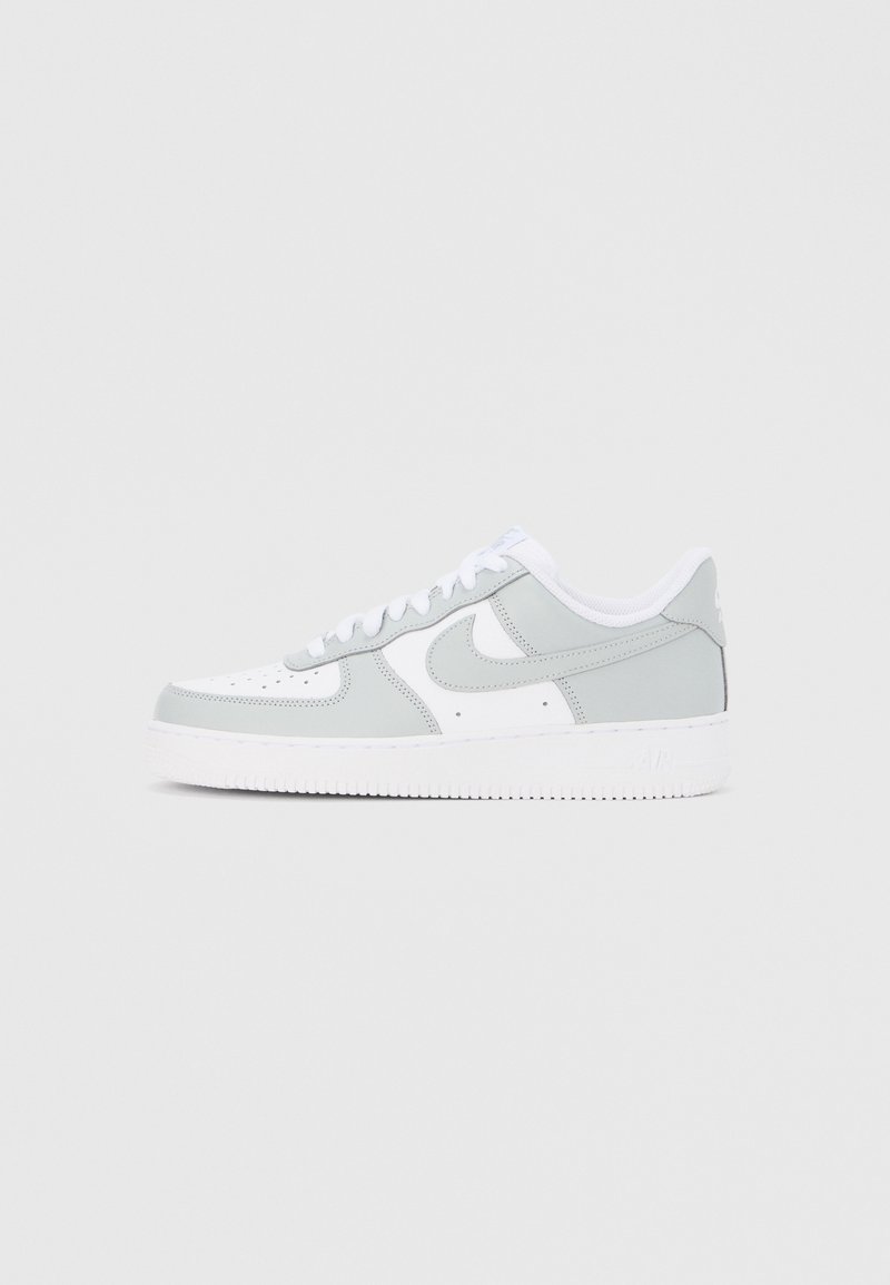 Basket basse Nike blanche et gris clair avec un laçage et une semelle blanche épaisse, montrée de profil sur un fond clair.