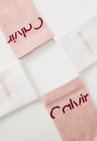 Kaks roosat ribakudumit sokki, millel on burgundia värvi "Calvin", ja kaks valget triibulist sokki, millel on helesinise värvi "Calvin Klein". Pehme kudumise tekstuur.