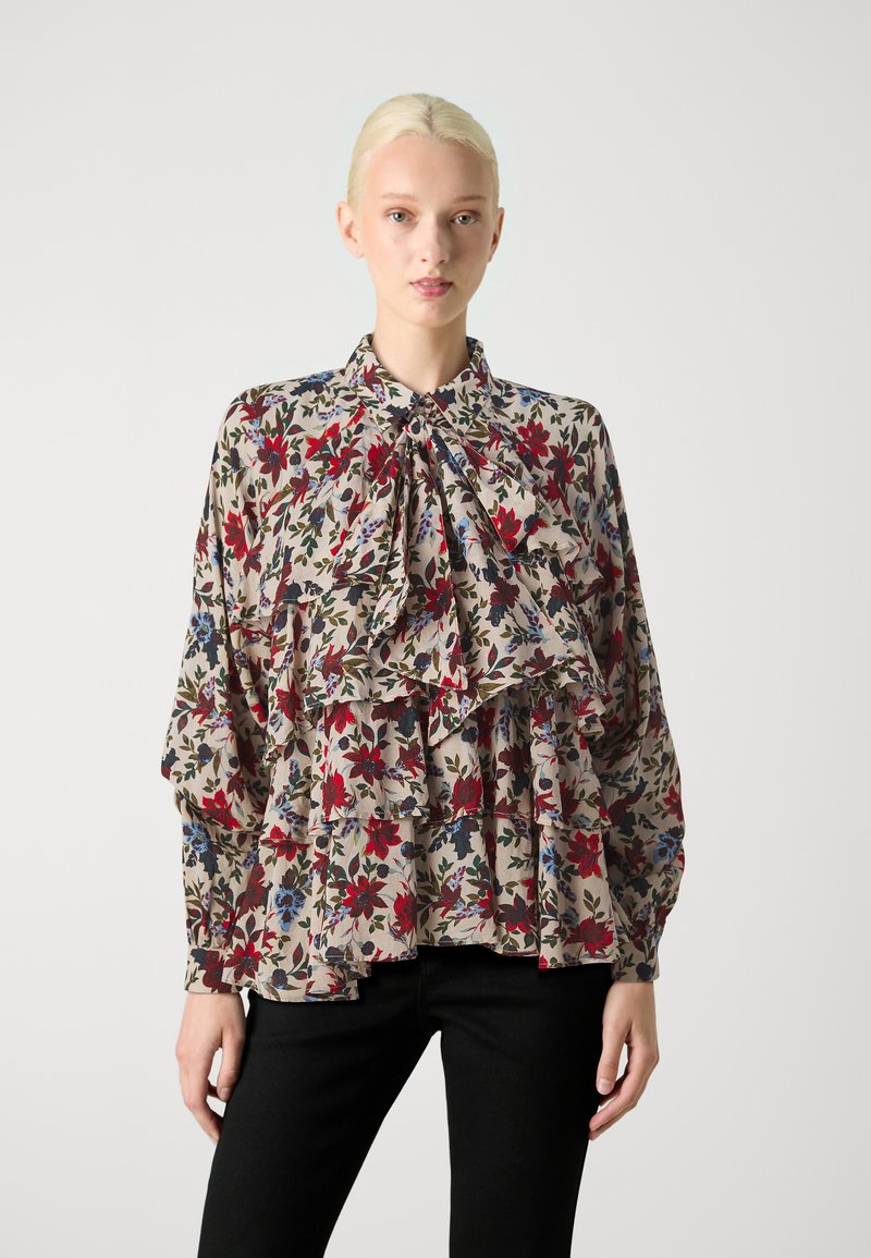 Bluse med blomsterprint i lys beige, med rynkede lag, en sløjfedetail ved kraven og lange ærmer. Sammen med sorte bukser.