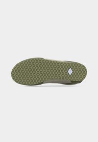 Semelle en caoutchouc vert olive avec motif de bande de roulement en forme de losange et petit logo Vans blanc près du talon sur une chaussure décontractée.