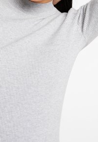 Szary, prążkowany sweter z golfem o dopasowanym kroju, z wysokim kołnierzem i teksturowanym materiałem, który zapewnia dodatkowe ciepło.